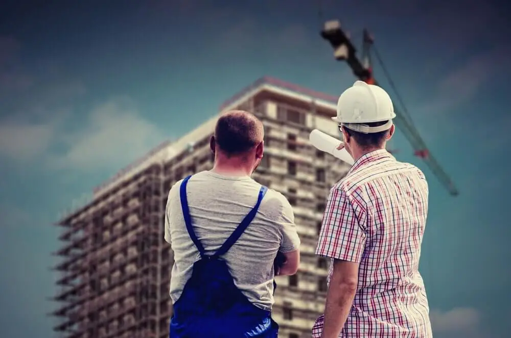 architect and builder looking up at a building under construction